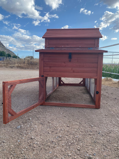 A red wooden chicken coop for 4+ chickens set outdoors with a partly cloudy sky in the background.