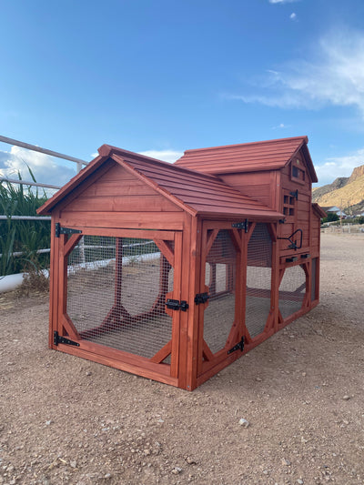 A red wooden chicken coop for 4+ chickens set outdoors with a partly cloudy sky in the background.