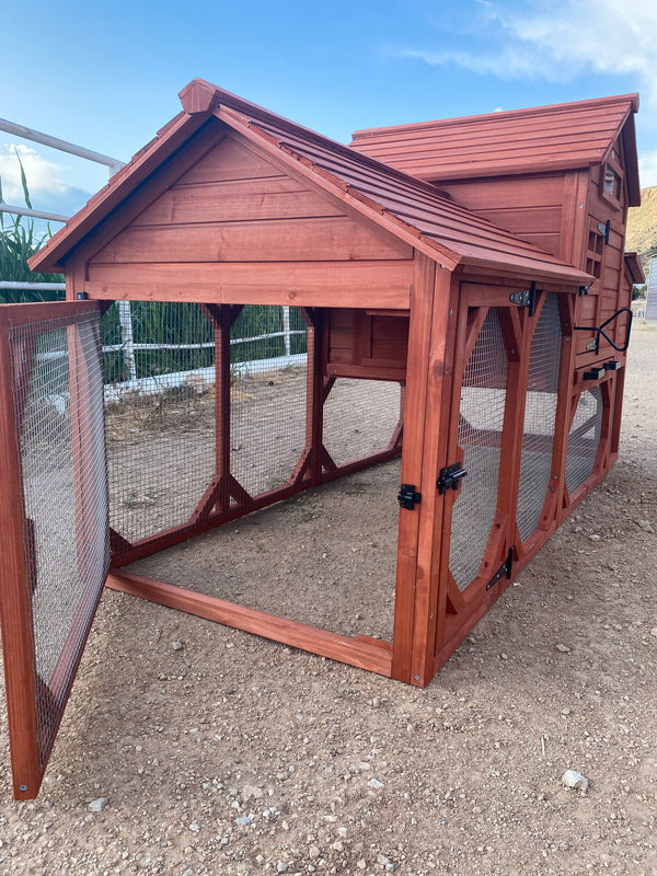 A red wooden chicken coop for 4+ chickens set outdoors with a partly cloudy sky in the background.