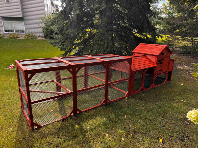 Leghorn Cottage Coop with run: elevated red wooden hen house, nesting spaces, wire-enclosed run, predator-resistant design in a lawn.