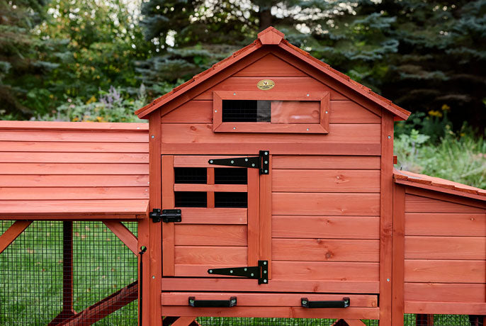 Red chicken coop detail showing the pull-out cleaning tray with handles and sliding mesh ventilation window.